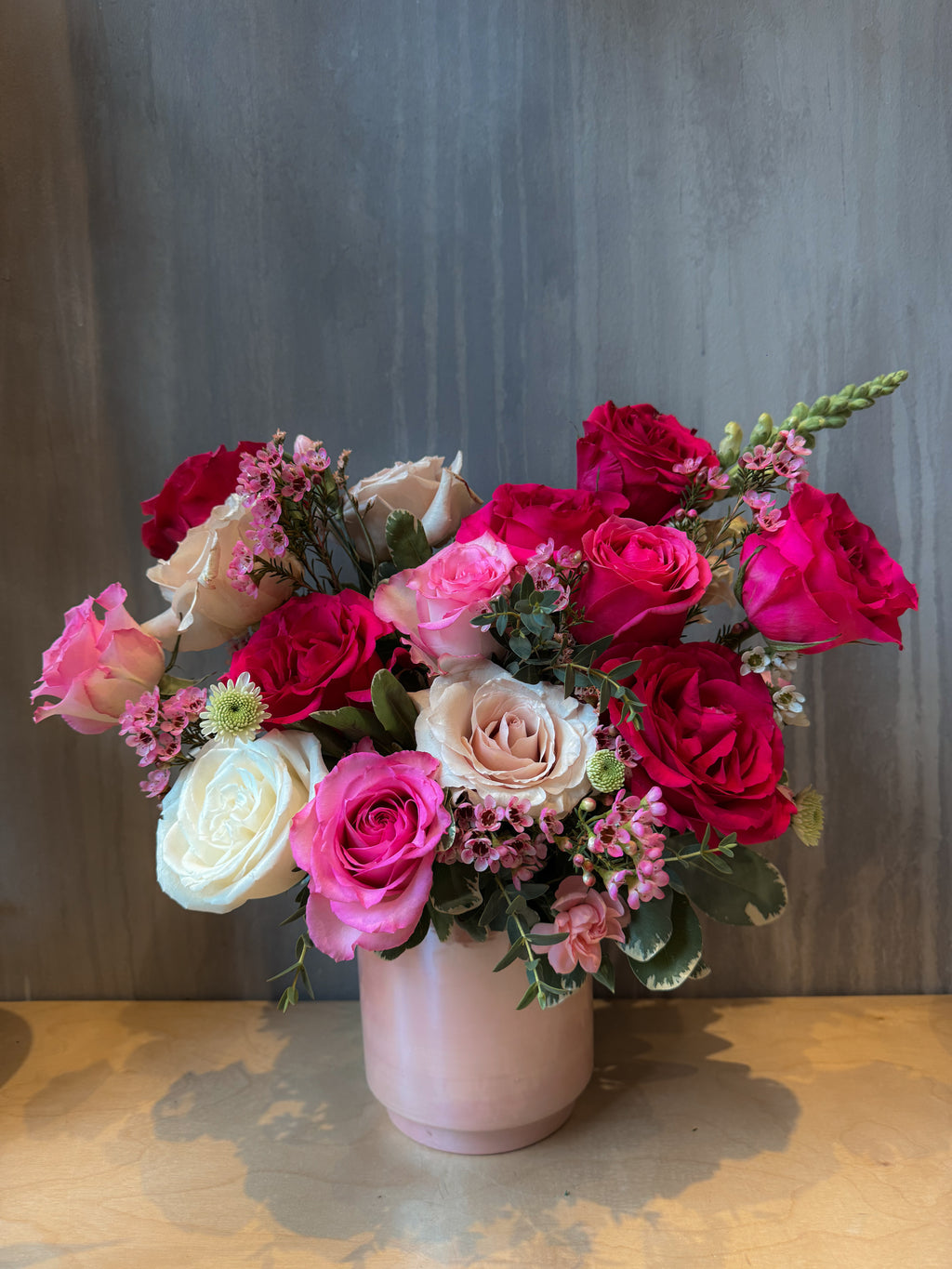 Pink and red rose flower arrangement in a glazed vase